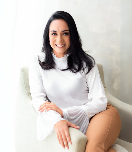Dra. Débora Andrade sentada em seu ambiente de atendimento